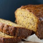 Moist pumpkin banana loaf sliced on wooden board with fall decor