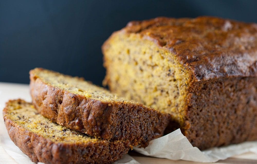 Moist pumpkin banana loaf sliced on wooden board with fall decor