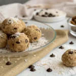 No-bake cookie balls labeled "Best Moose Farts Recipe" on glass plate with coconut, chocolate chips, and graham crumbs.