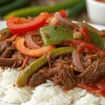 Tender shredded beef with peppers and onions served over white rice – ropa vieja recipe slow cooker