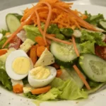 Chef salad with olive oil dressing, eggs, lettuce, cucumbers, and tomatoes