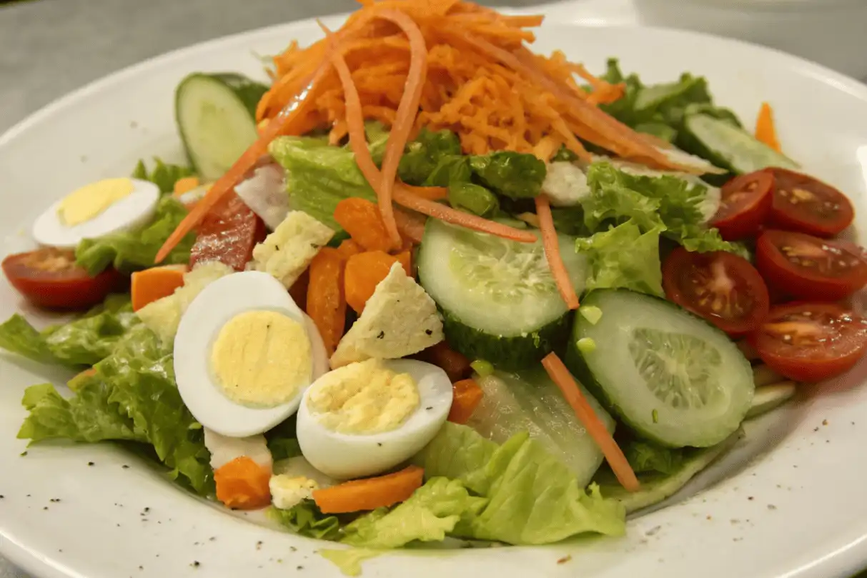 Chef salad with olive oil dressing, eggs, lettuce, cucumbers, and tomatoes