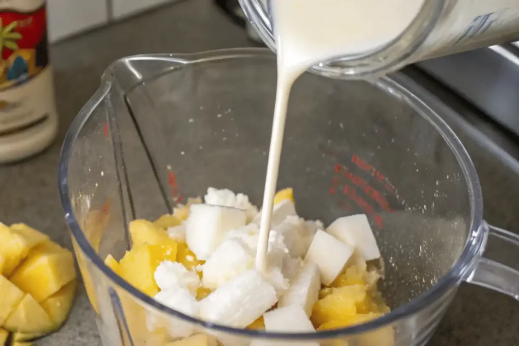 Coco Lopez cream of coconut pouring into blender for authentic piña colada