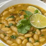A bowl of Mayocoba bean soup topped with fresh cilantro and lime slices