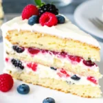 Slice of berry chantilly cake with fresh berries and mascarpone cream frosting