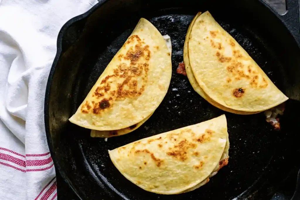 Crispy tacos folded and grilled in a cast iron skillet on wooden table