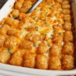 Buffalo chicken tater tot casserole baked with melted cheese and crispy tots in a white dish