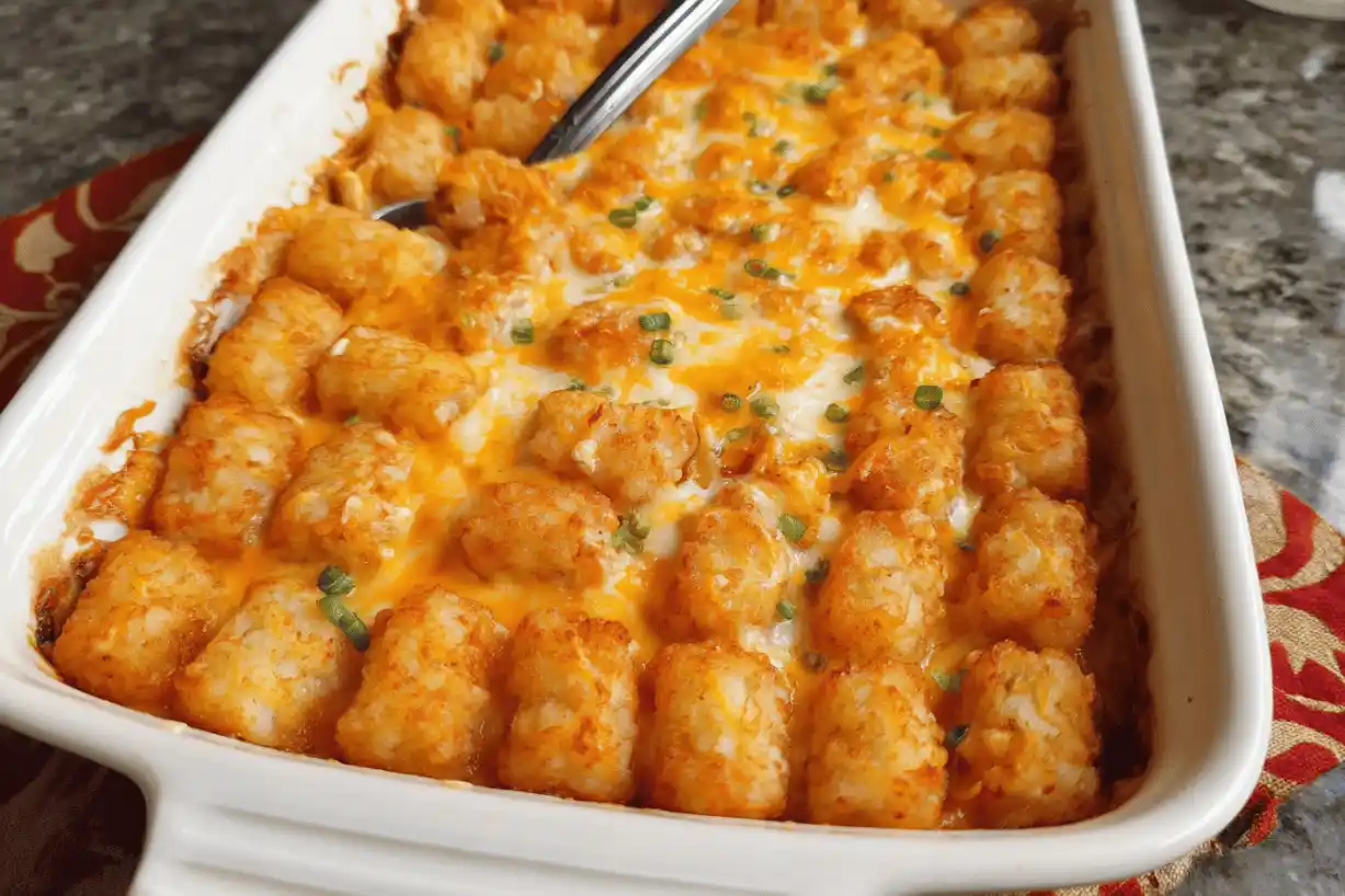 Buffalo chicken tater tot casserole baked with melted cheese and crispy tots in a white dish
