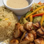 Hibachi chicken recipe plated with buttery rice, stir-fried vegetables, and creamy yum yum sauce