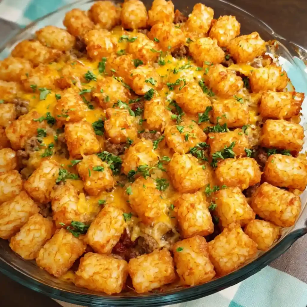 Beef and cheese mixture spread in baking dish topped with frozen tater tots.