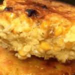 Cream cheese corn casserole with golden cheesy top and creamy corn center served from round baking dish