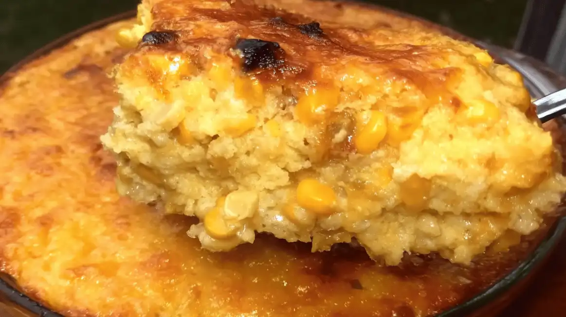 Cream cheese corn casserole with golden cheesy top and creamy corn center served from round baking dish